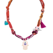 Colorful fabric necklace with tassels and a hamsa charm on a white background