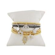 Set of gold and silver bracelets on a white cushion