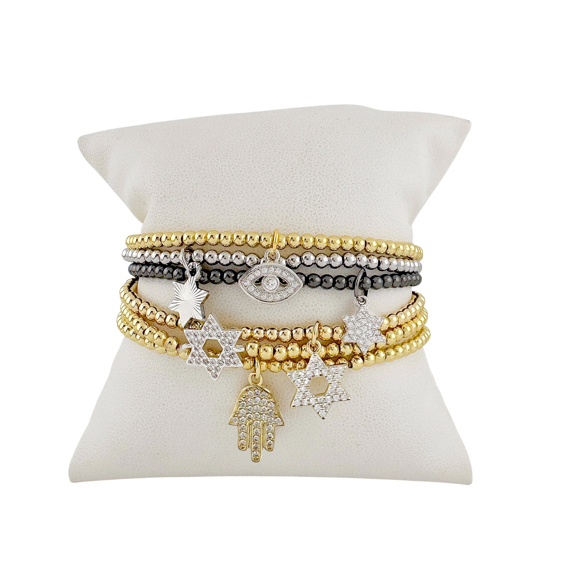 Set of gold and silver bracelets on a white cushion