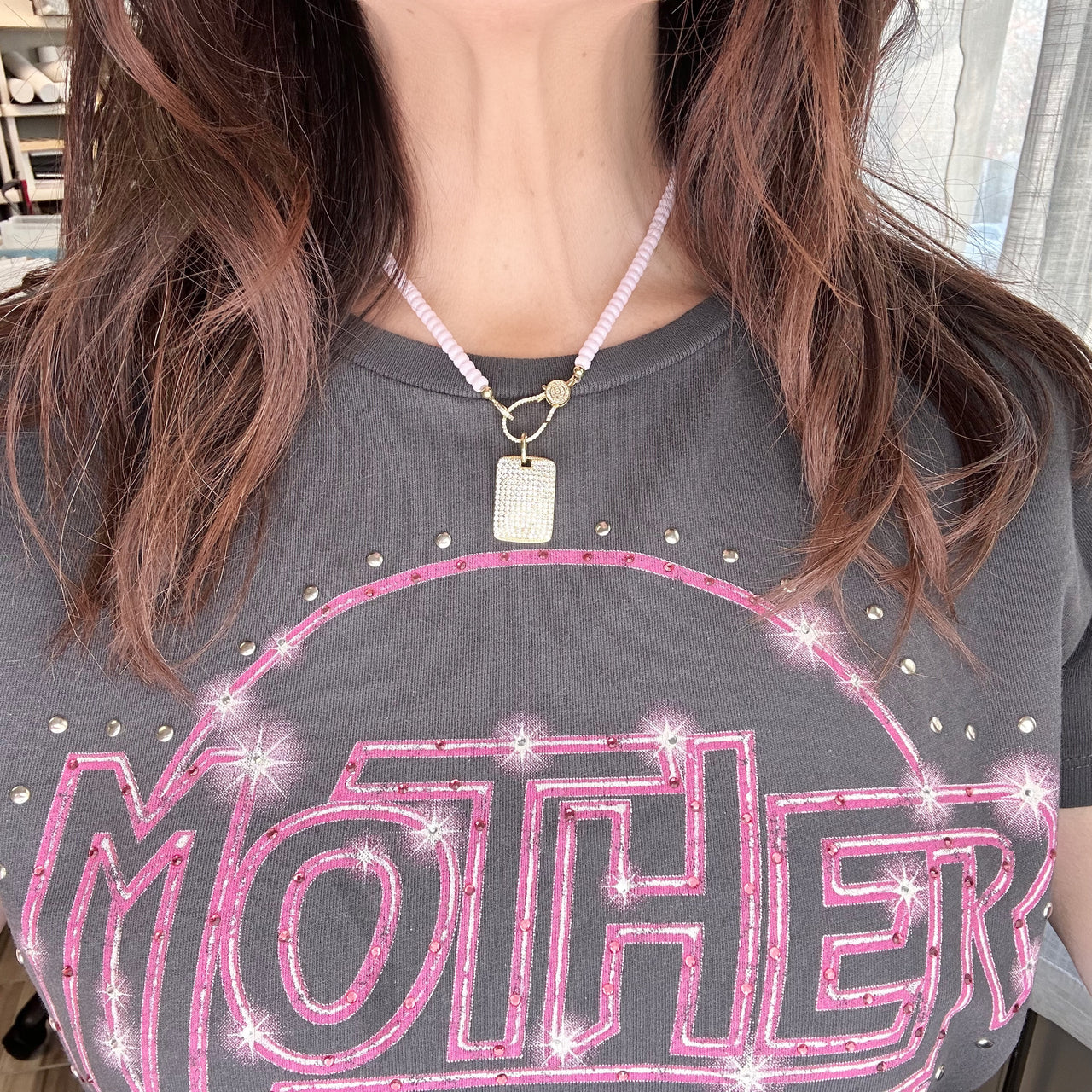 Woman wearing Stella Dog Tag Charm on Harper pink beaded Love Lisa necklace with 'Mother' shirt