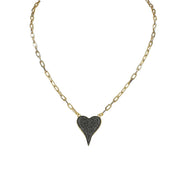 A gold-colored necklace with a paperclip chain and a heart-shaped pendant with black crystals.