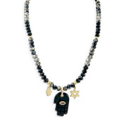 ove Lisa Amalia Gemstone Hamsa Protection Necklace with black and grey rondelle beads, large black gemstone Hamsa pendant, petite gold-tone Hamsa, Star of David charm, and CZ accents on white