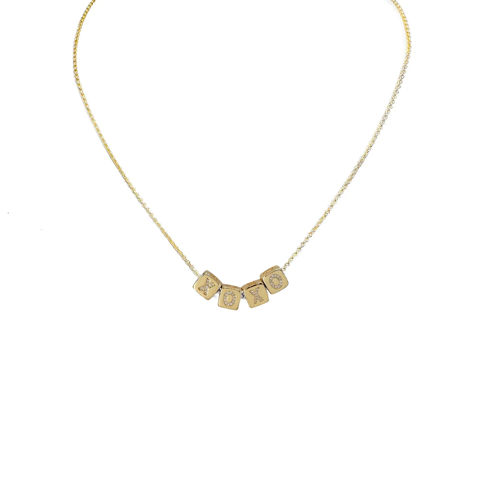 A personalized necklace with gold chain and silver block letter beads.