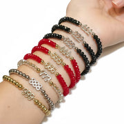 Angel Number Bracelets by Love Lisa stacked on wrist in red, black, and gold beaded designs