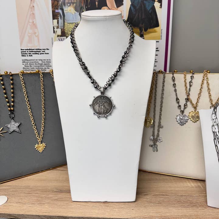 angelica french coin necklace displayed on stand showing silver pendant and gunmetal chain love lisa