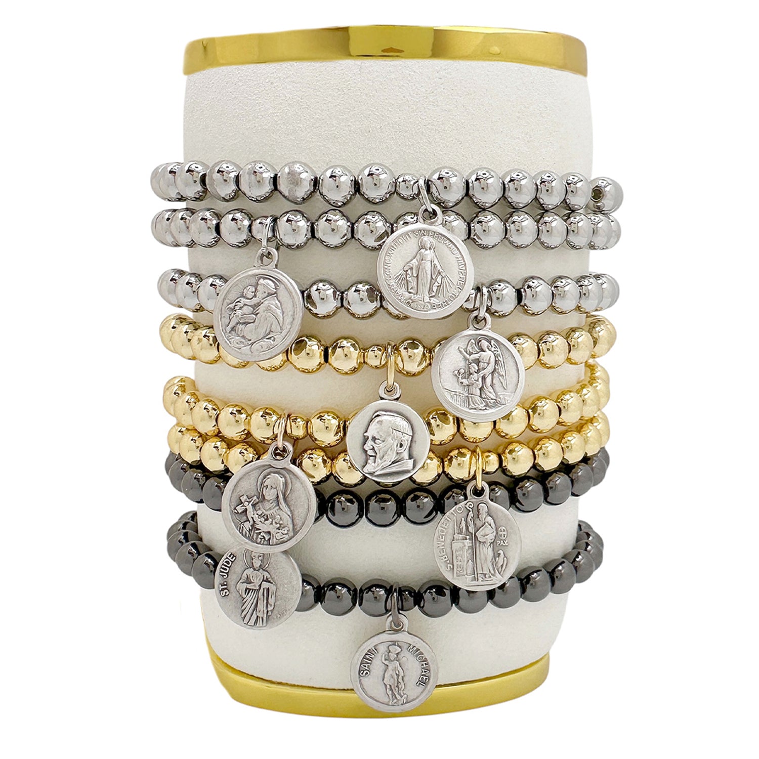 A collection of beaded bracelets with various metallic finishes and Saint medals displayed on a cylindrical stand.