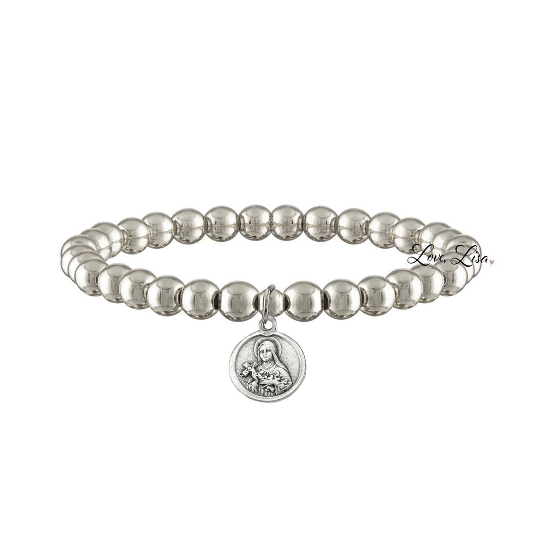 A collection of beaded bracelets with various metallic finishes and Saint medals.