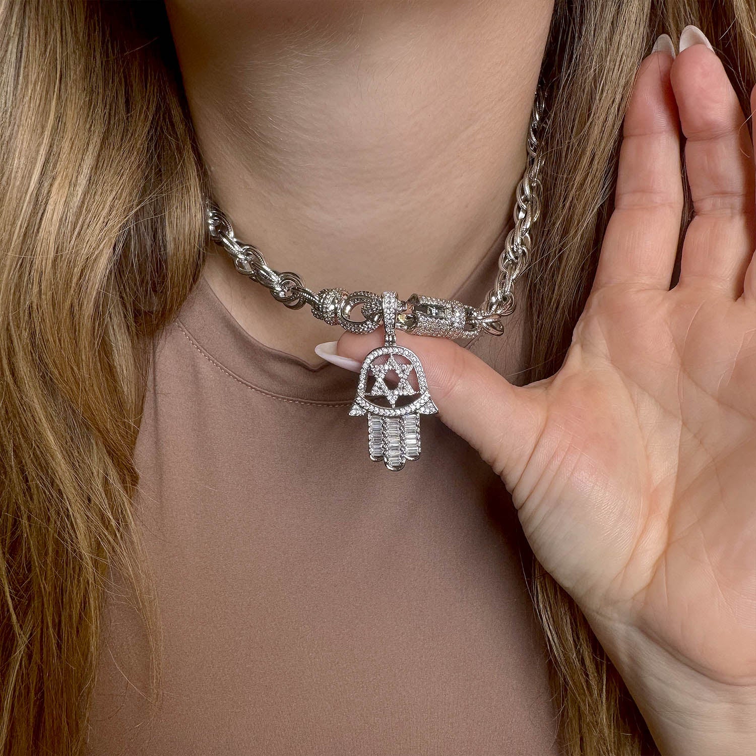 Silver chain bracelet with a Hamsa hand charm worn by a person.