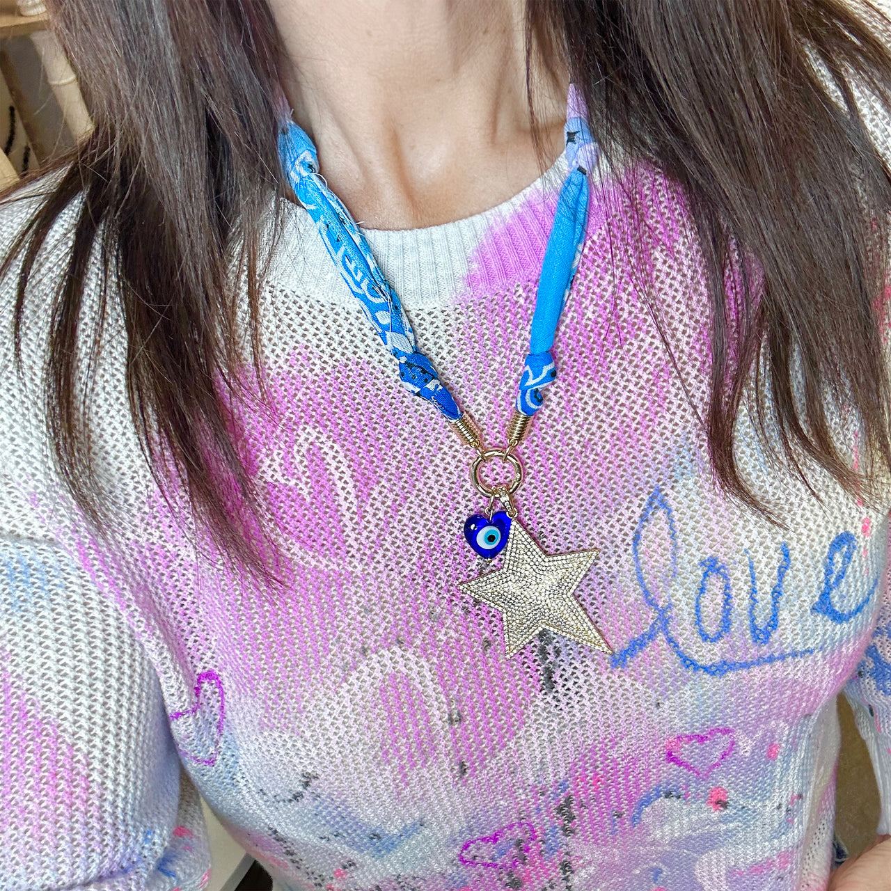 Person wearing a colorful shirt with a star-shaped pendant
