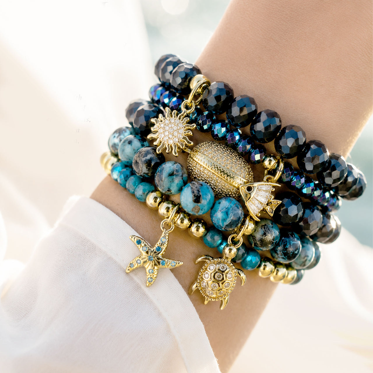 Love Lisa Azure Coast bracelet stack worn on wrist with navy blue beads turquoise sea sediment stones and gold coastal charms