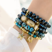 Love Lisa Azure Coast bracelet stack worn on wrist with navy blue beads turquoise sea sediment stones and gold coastal charms