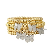 A stack of gold-colored beaded bracelets featuring butterfly charms, showcasing varying sizes of beads.
