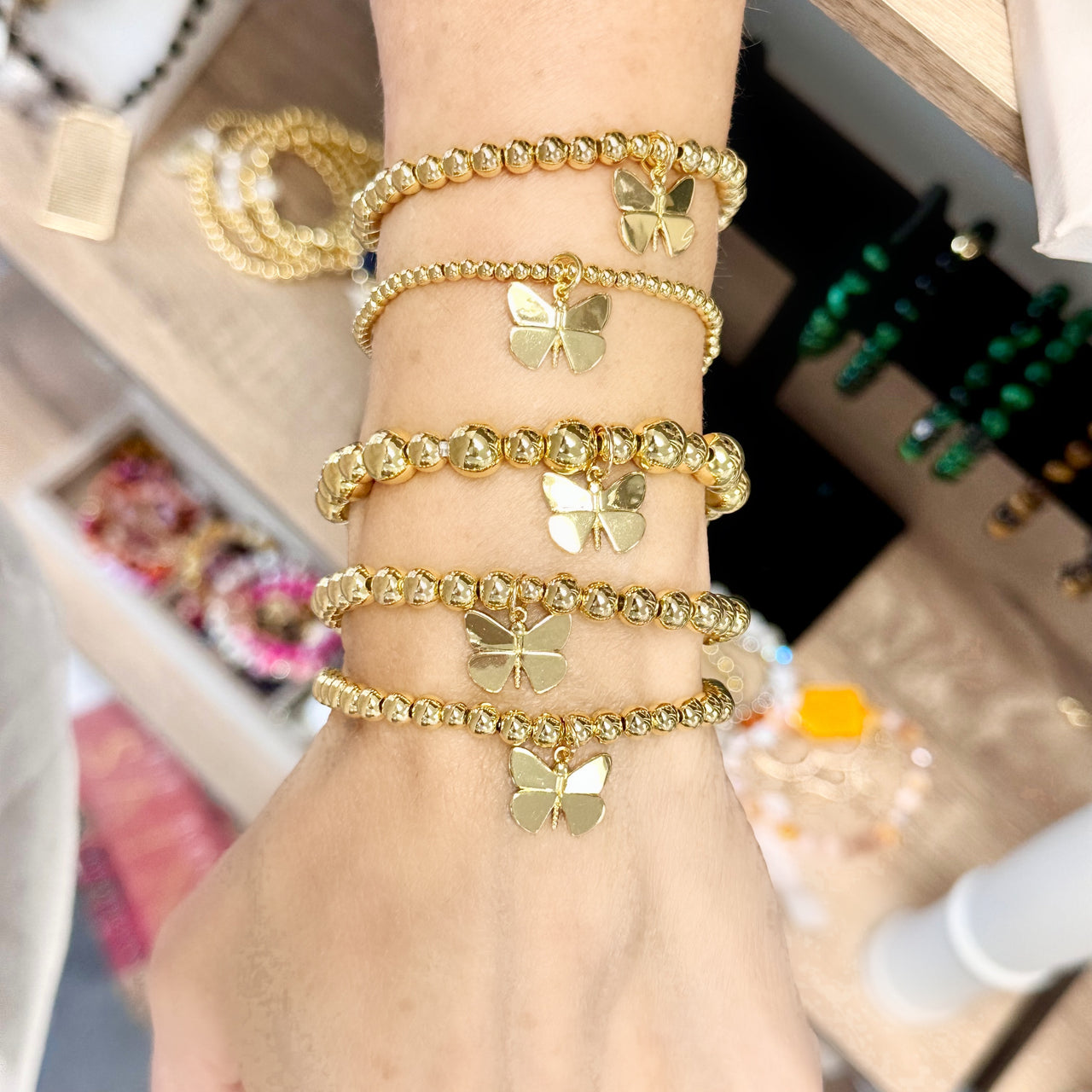 bailey butterfly beaded bracelet stack worn on wrist gold stretch bracelets with butterfly charms by love lisa