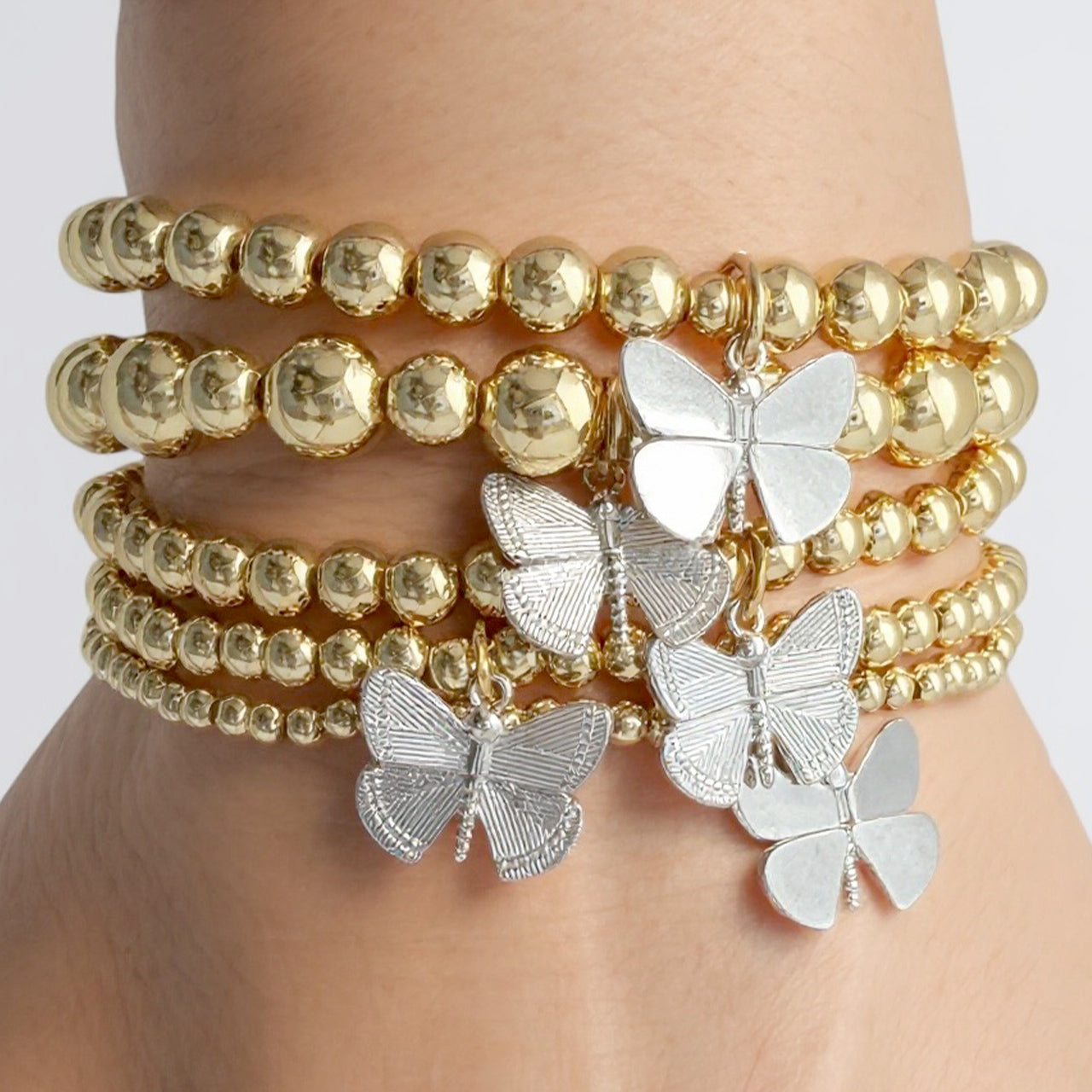 bailey butterfly beaded bracelet stack worn on wrist gold stretch bracelets with butterfly charms by love lisa