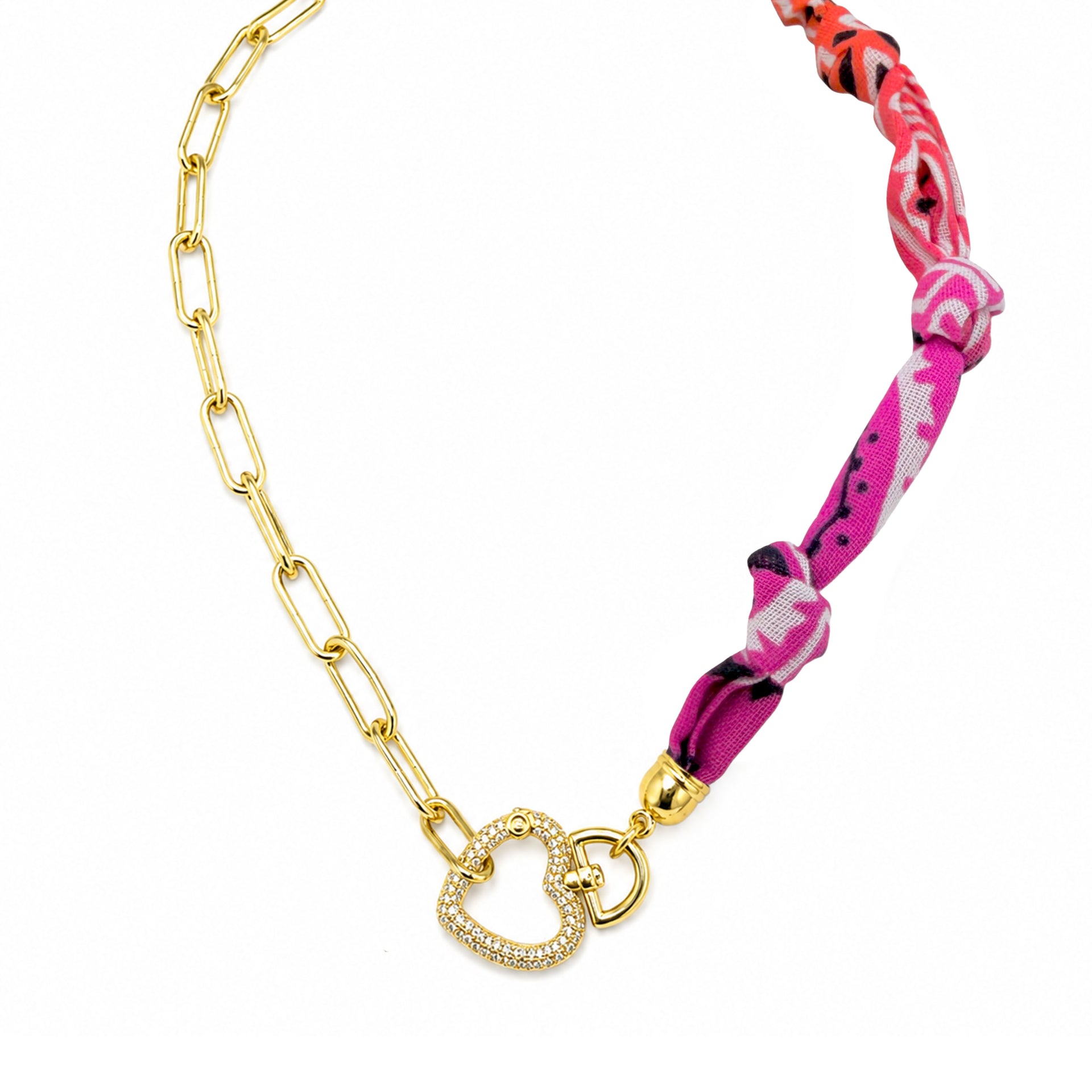 A gold chain necklace featuring a central double heart charm encrusted with small clear stones, connected to a gold paperclip chain and a vibrant pink, red, and white patterned fabric wrap, shown on a white background.