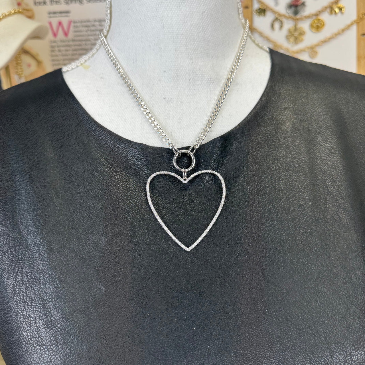Silver open heart charm with smooth, modern silhouette on display