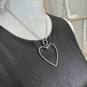 Delicate silver heart pendant with open frame design on display