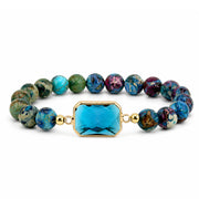 Bellissima Emerald Cut Crystal Gemstone Bracelet in Teal with blue green gemstone beads, gold-tone accents, and aqua crystal centerpiece
