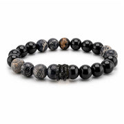 A beaded stretch bracelet featuring a mix of polished black beads, matte black-and-white marbled beads, and a textured black spacer, displayed on a clean white background.