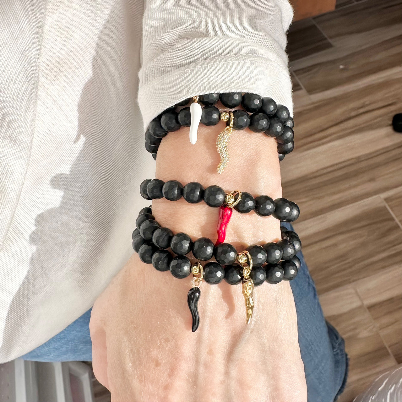 black onyx italian horn cornicello bracelet worn on wrist layered with other love lisa gemstone bracelets