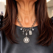 Love Lisa Blessed & Protected Catholic Saint Charm Necklace worn at the neckline with layered silver-tone religious medals, crucifix, and crystal charms