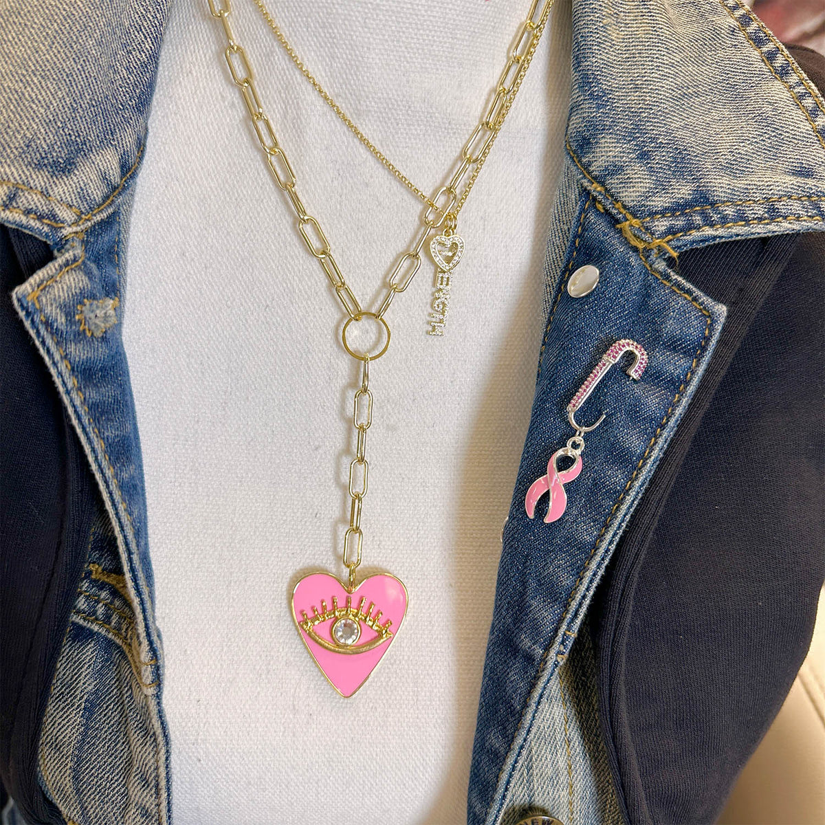 Love Lisa Breast Cancer Awareness Pink Ribbon Safety Pin worn on denim jacket with pink ribbon charm and layered necklace styling