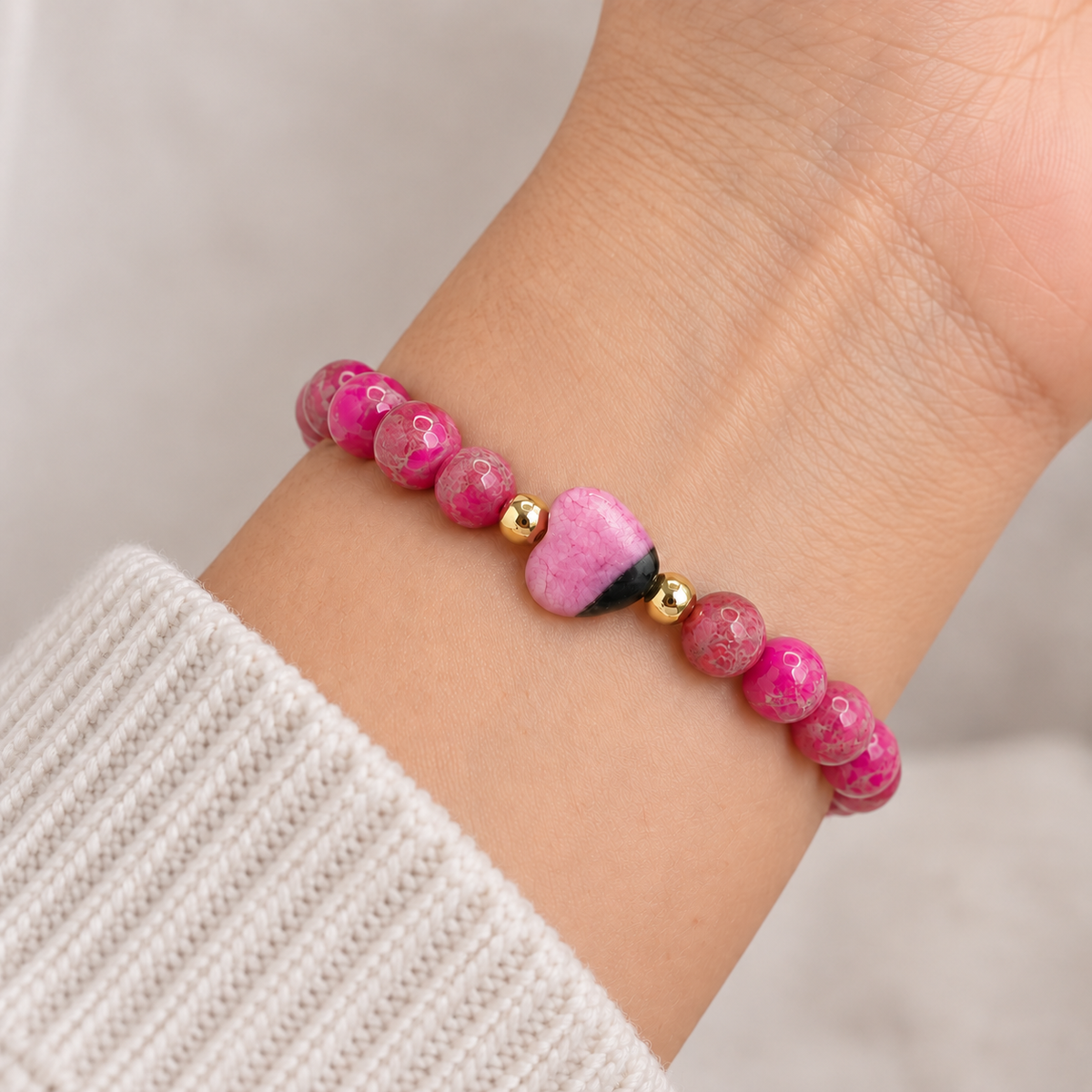Pink sea sediment jasper worry stone bracelet worn on wrist with smooth heart-shaped focal bead