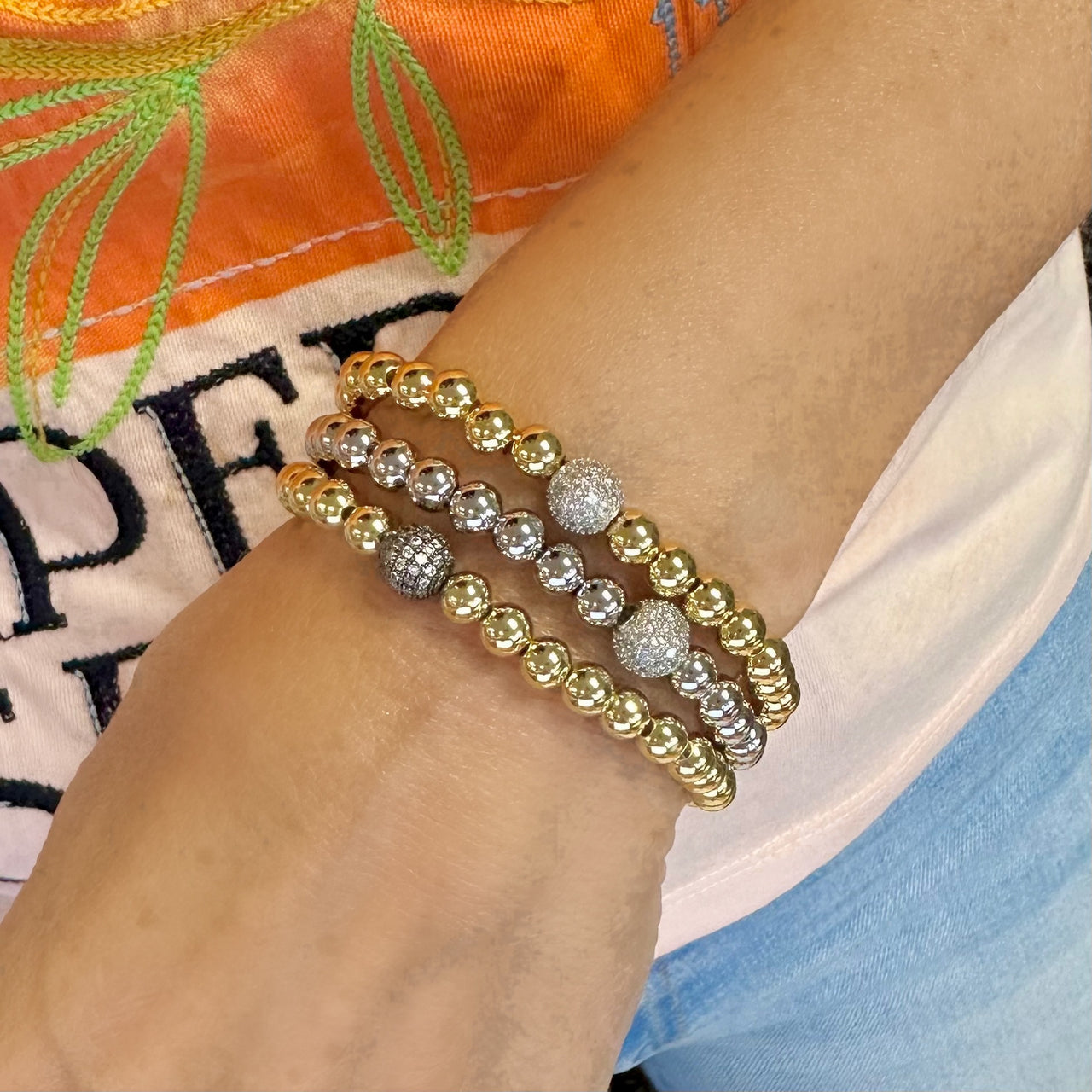 Pavé ball stretch bracelet with gold and silver beaded layers on wrist

