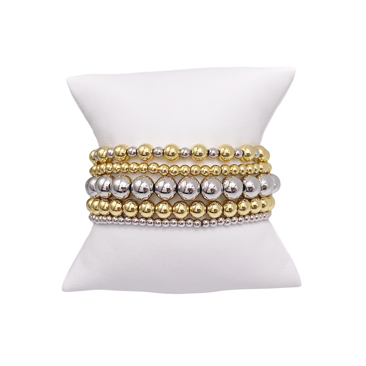 A set of beaded bracelets displayed on a white stand, featuring a combination of gold and silver colored beads.