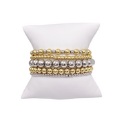 A set of beaded bracelets displayed on a white stand, featuring a combination of gold and silver colored beads.