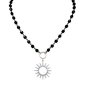 Flatlay of silver sun beaded necklace on black beads