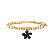A gold-colored bracelet featuring a floral charm with black accents on a white background.