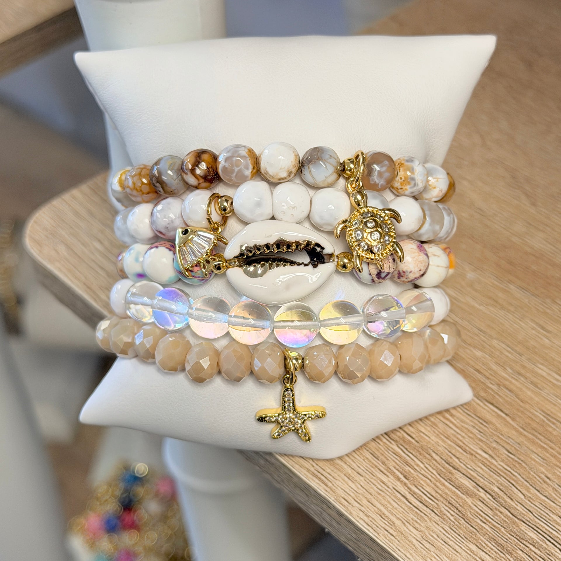 Love Lisa Coastal Sandbar bracelet stack displayed on pillow with ivory gemstone beads iridescent crystals and gold coastal charms