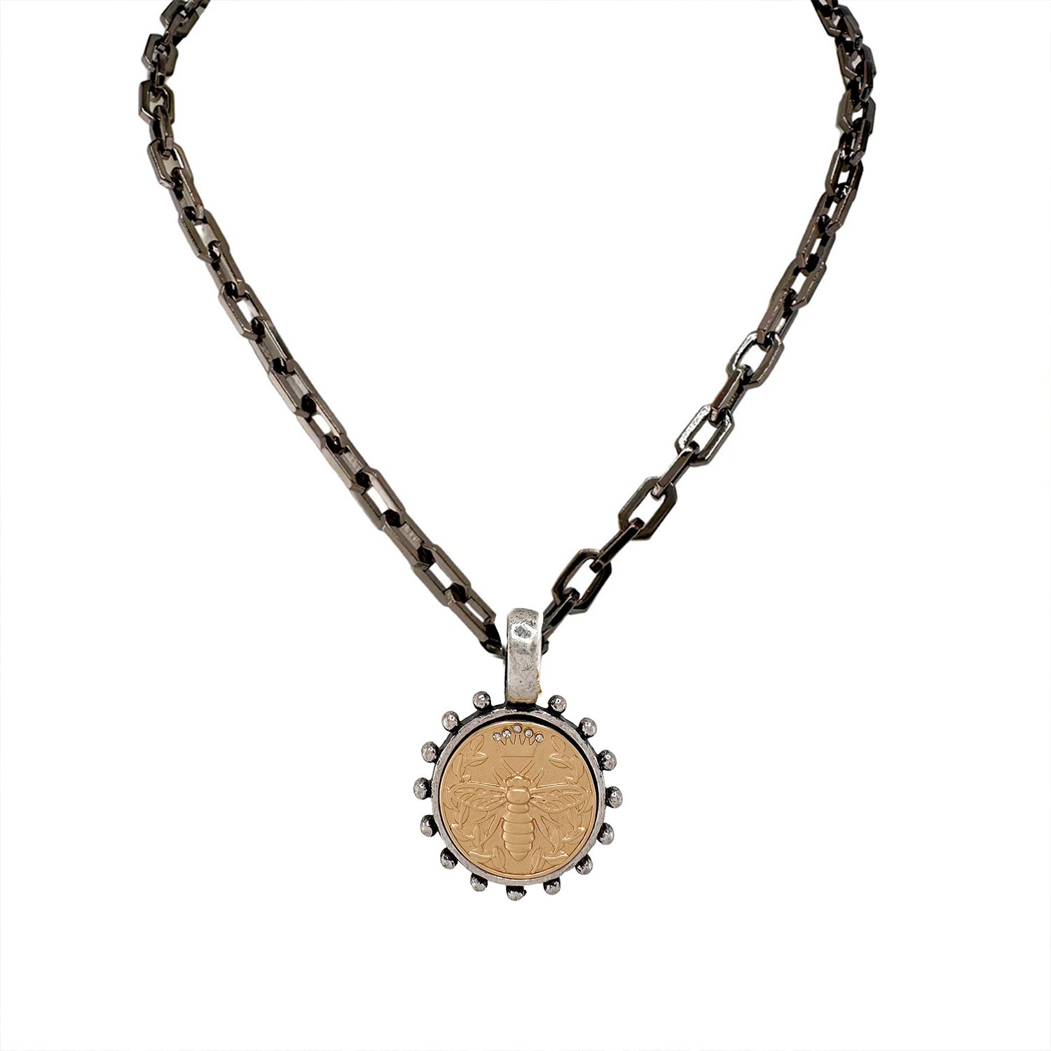 A gunmetal link chain necklace with a circular bee coin pendant in gold.