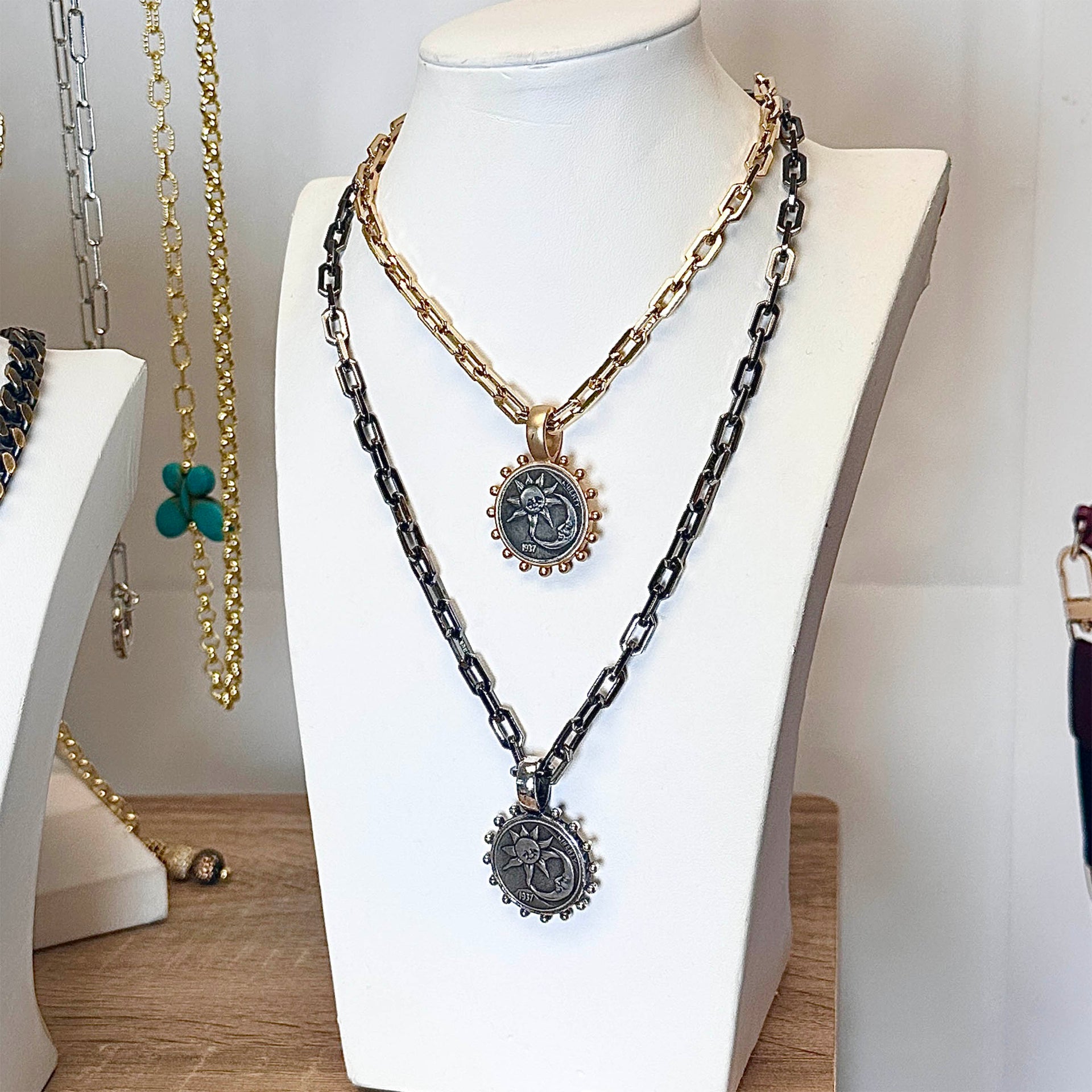 Necklace with chain design and pendant on a mannequin bust against a neutral background