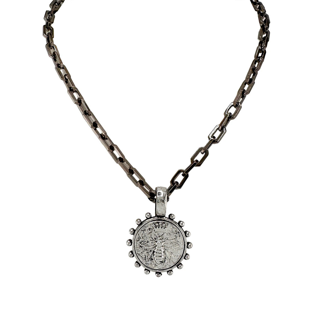 A gunmetal link chain necklace with a circular bee coin pendant.