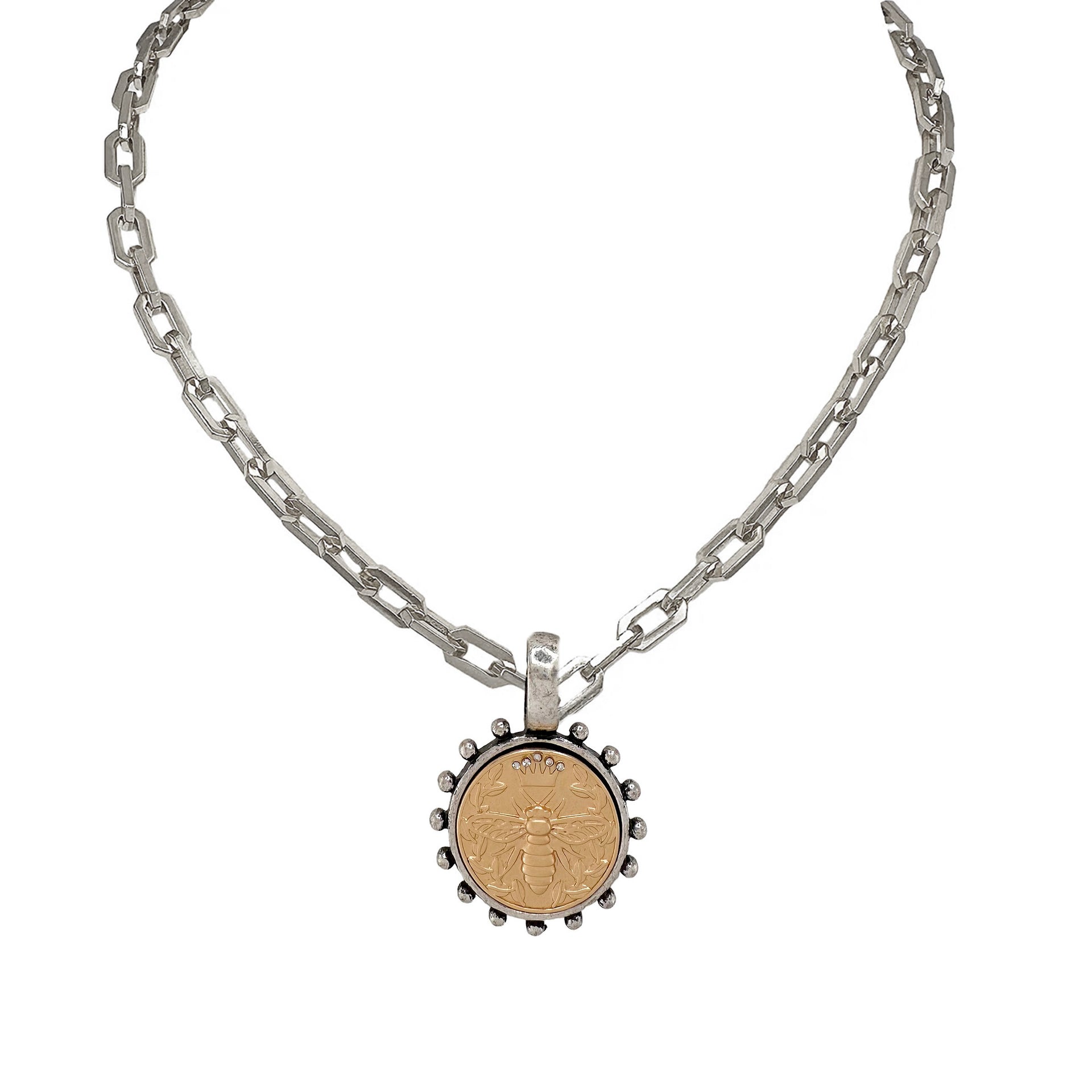 A silver link chain necklace with a circular bee coin pendant.