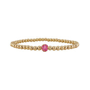 Gold beaded bracelet with a pink gemstone on a white background