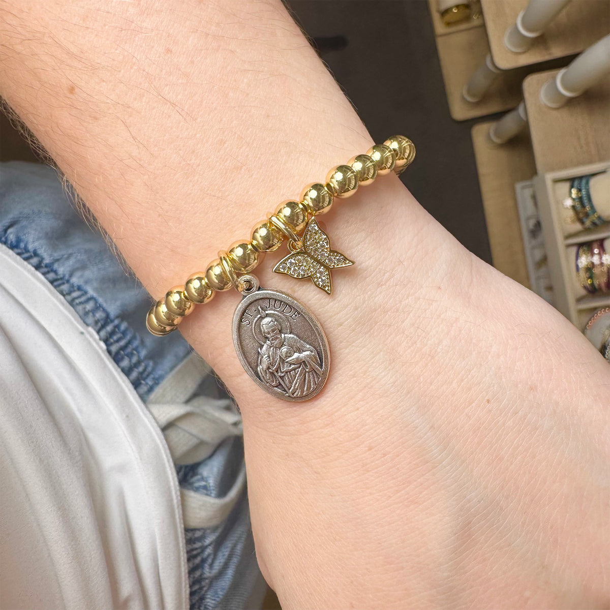 Love Lisa Saint Jude Butterfly Bracelet worn on wrist with gold beads, Saint Jude medal, and butterfly charm