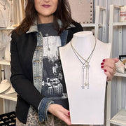 Person holding a necklace on a mannequin bust in a store setting