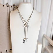 Necklace with star and hand of faith charms on a mannequin bust against a white curtain background.