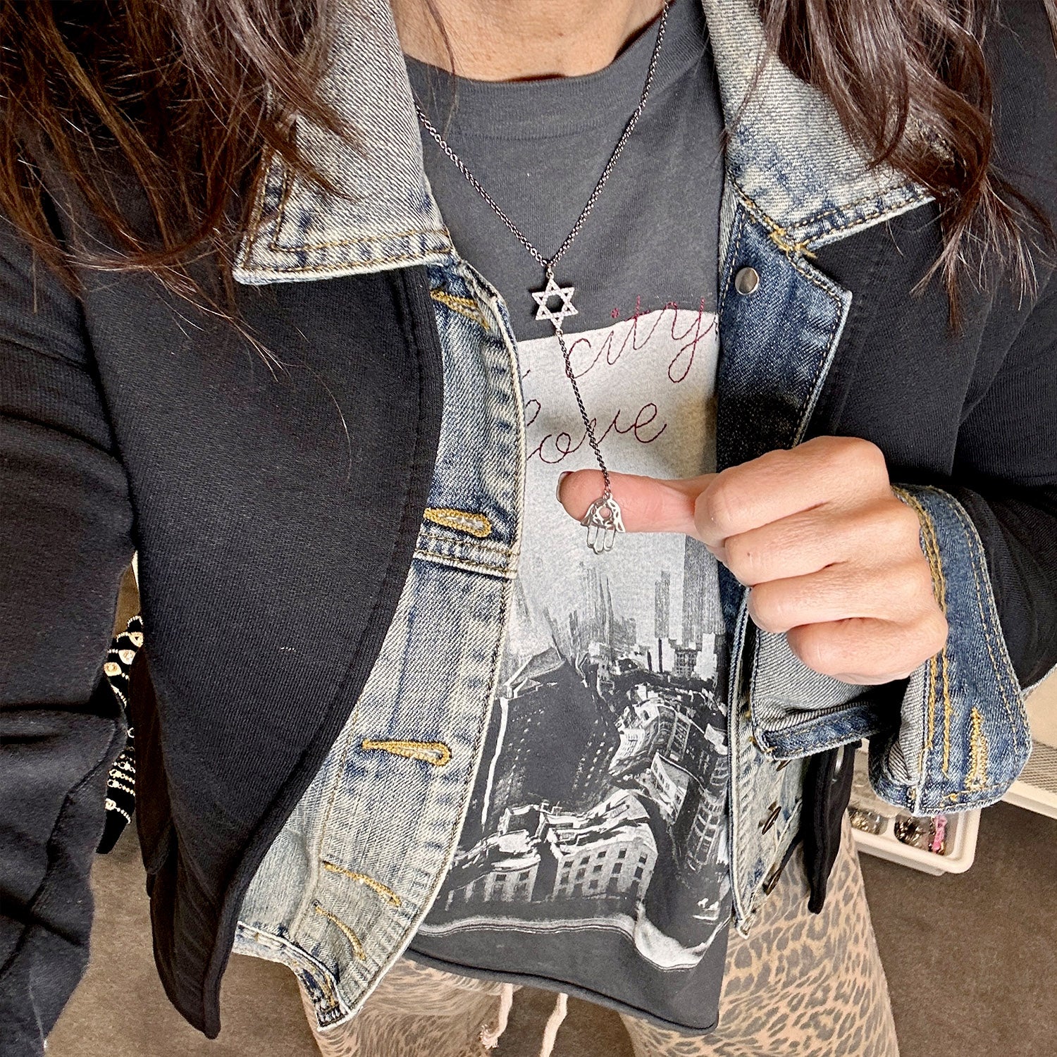 Person wearing a denim jacket over a graphic t-shirt with a cityscape design.