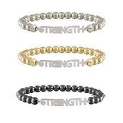 Three 'STRENGTH' beaded bracelets in silver, gold, and black on a white background.