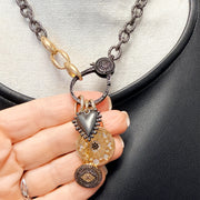 Close-up of Love Lisa Estelle necklace showing celestial moon and star medallion, dimensional heart charm, sparkling evil eye, and crystal-accented clasp