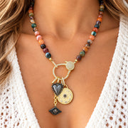 Love Lisa Estelle gemstone charm necklace worn at the neckline with multicolor faceted agate beads and mixed-metal moon, heart, and evil eye charms