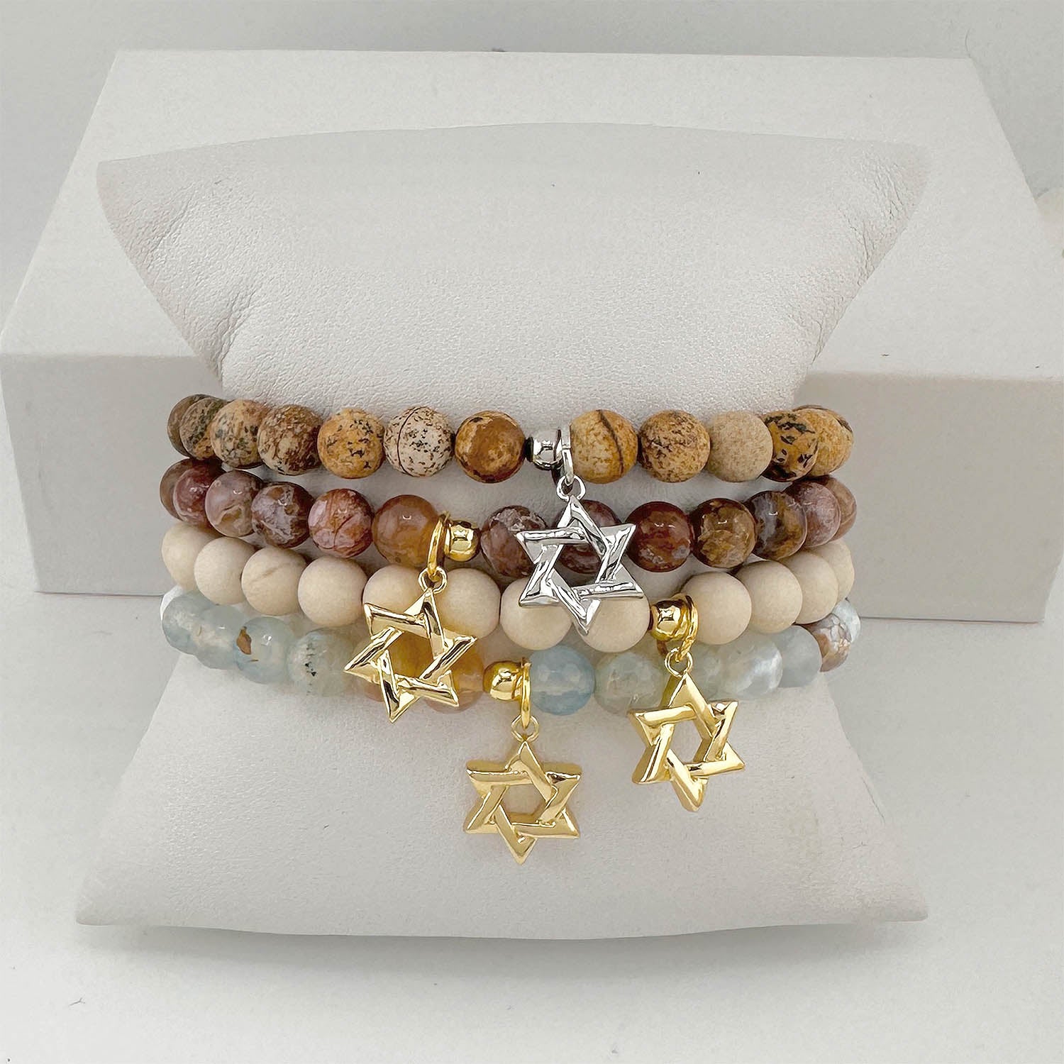 Stack of beaded bracelets with Star of David charms on a white surface