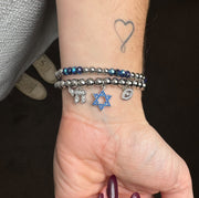 love lisa silver faith and protection charm bracelet worn on wrist with star of david chai charm and evil eye