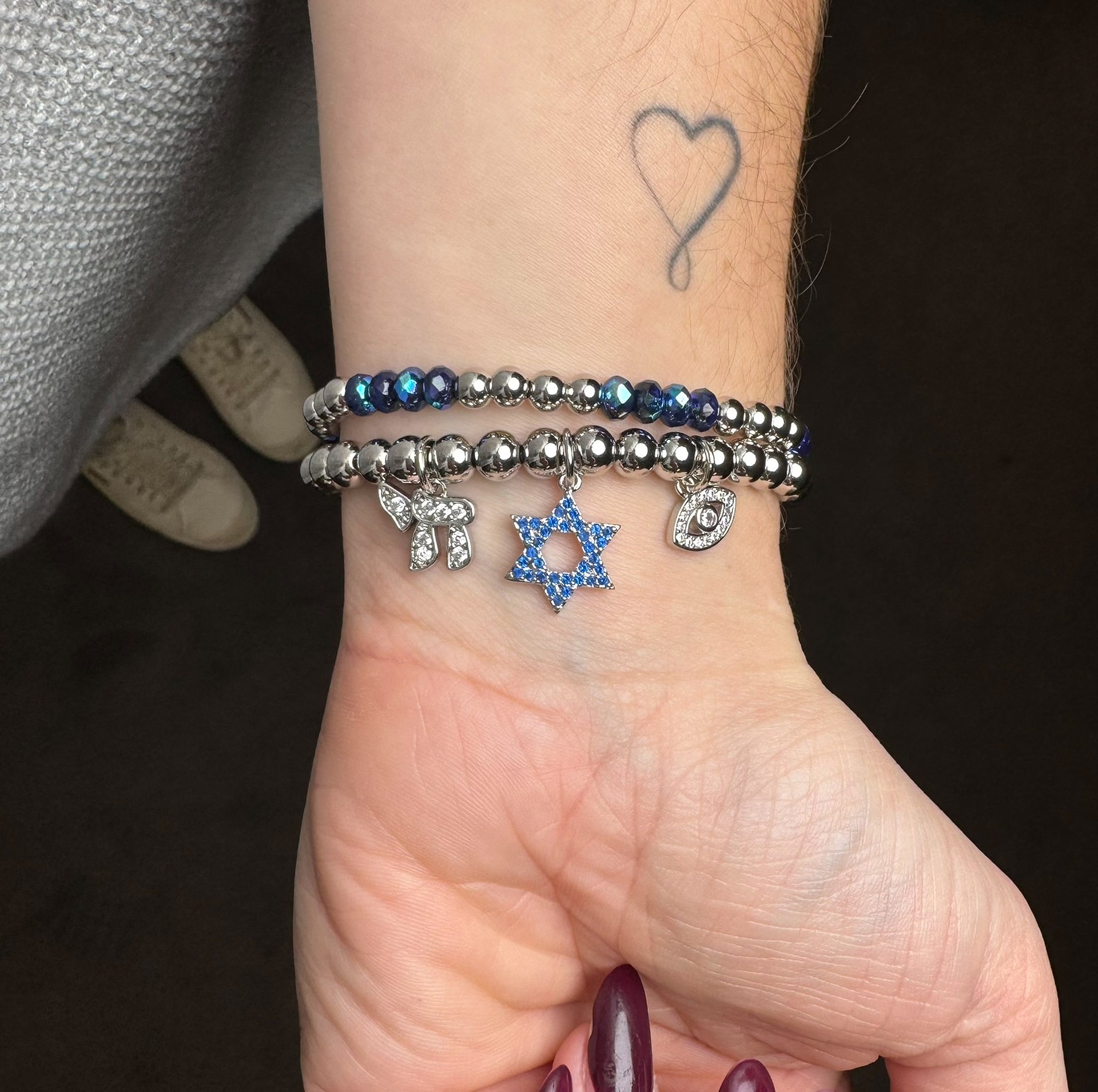 love lisa silver faith and protection charm bracelet worn on wrist with star of david chai charm and evil eye