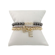 gold and silver mixed metal flower initial charm bracelet with crystal flower charm and pave initial charm on display pillow