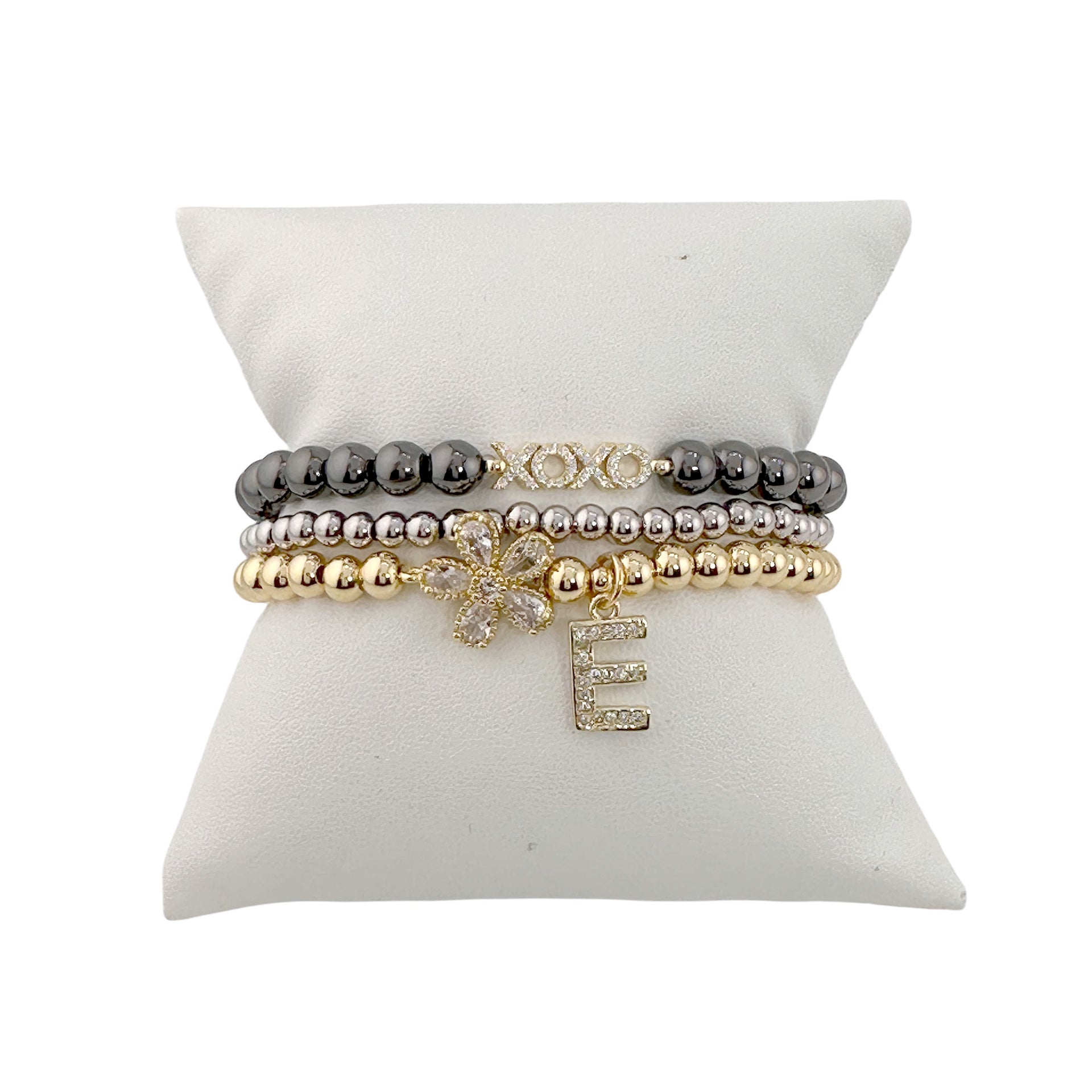 gold and silver mixed metal flower initial charm bracelet with crystal flower charm and pave initial charm on display pillow